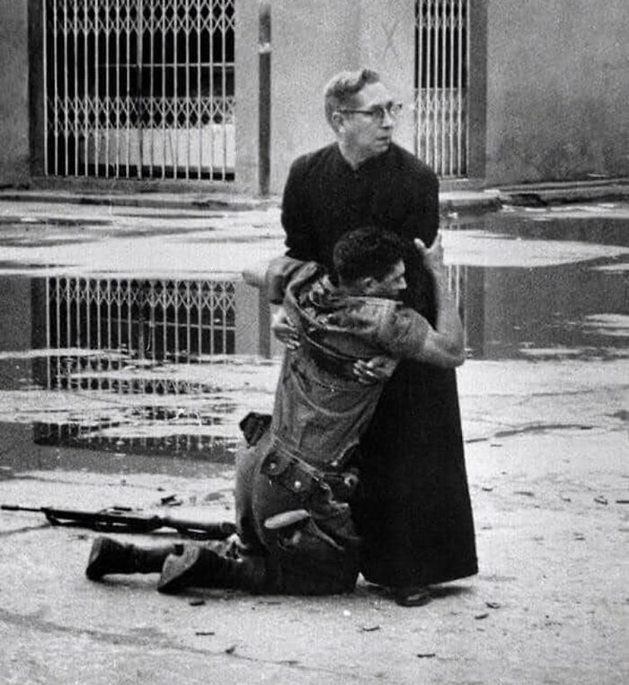 fascinating photos form history  - A Priest Holds A Dying Soldier Whilst Bullets Are Fired Around Them | Venezuela, 1962