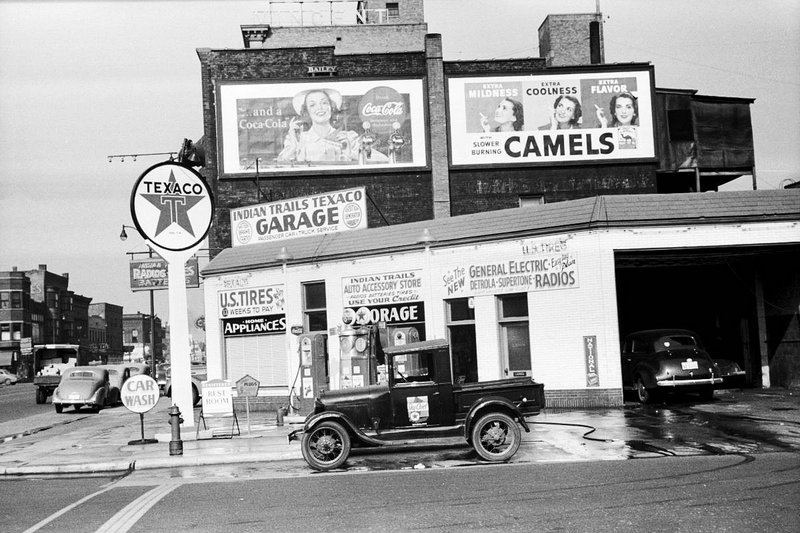 historical photos - gas station 1940 - Batury Srtea Extra Mildness Coolness Sta Flavor Car Cell and a CocaCola Slower Burning Camels Texaco Indian Trails Texaco Garage Radiog Batte Indian Trails Auto Accessory Store Tags Use Your Credil Sette General Elec
