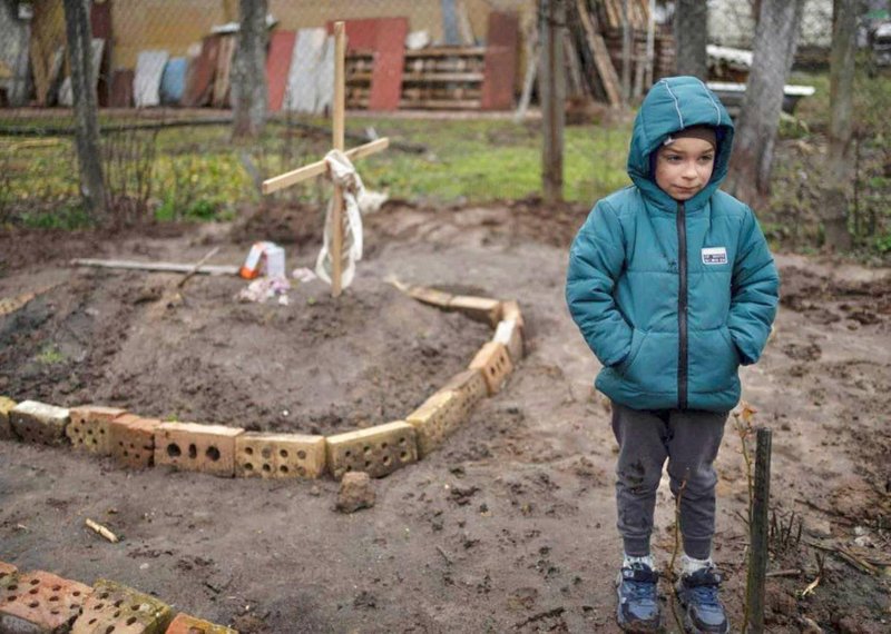 A 6 year old Ukrainian boy standing near his own mother’s grave