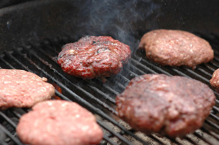 When you're cooking burgers with any method, make a small dent on the top of the patty (right in the center) with your thumb. When they cook, they'll stay completely flat instead of shrinking and getting very tall in the middle