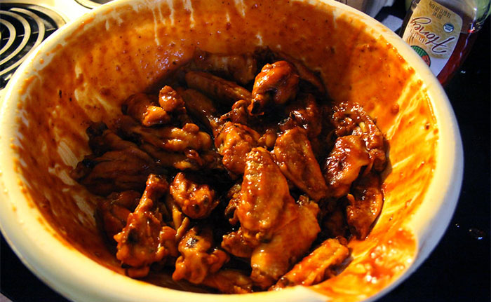 If you swirl the hot wings around in the bottom of the sauce bowl for about eight seconds before tumbling them, the oil in the sauce (butter - what have you) breaks down in the heat first and you get a better coverage when you tumble / flip them.