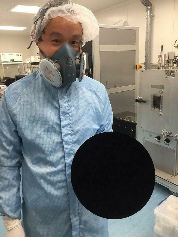 A scientist holding a basketball covered in vantablack, the world's blackest substance. 