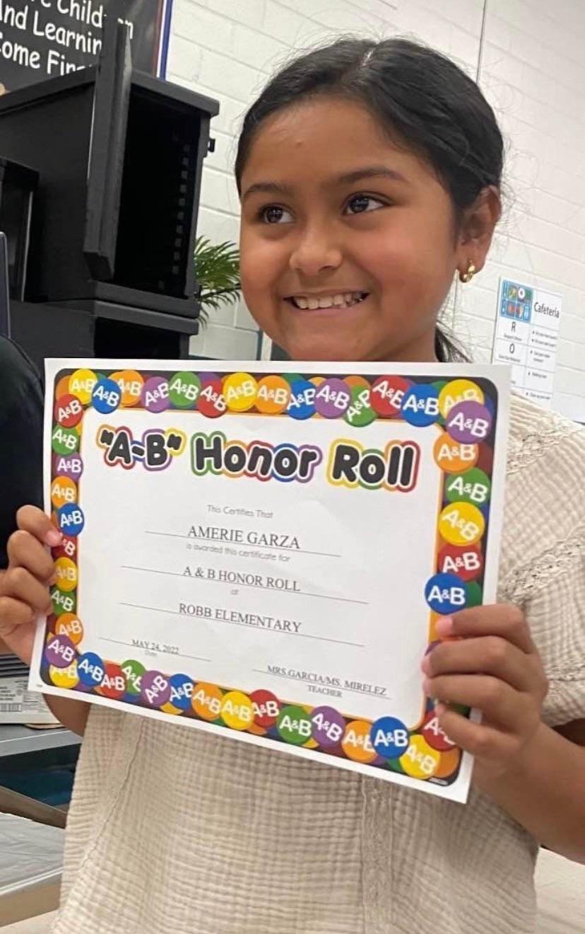 10-year-old Amerie Jo Garza holds up a school certificate naming her to the honor roll at Robb Elementary School in Uvalde, Texas at 10 a.m. Tuesday. Hours later she would be killed at school.