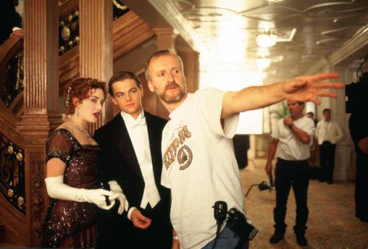 behind the scenes movies - Kate Winslet and Leonardo DiCaprio stare while director James Cameron points to something on set of Titanic (1997). I love Kate's face here because it 100% looks like James is a time-traveller sent back in time to tell her some 
