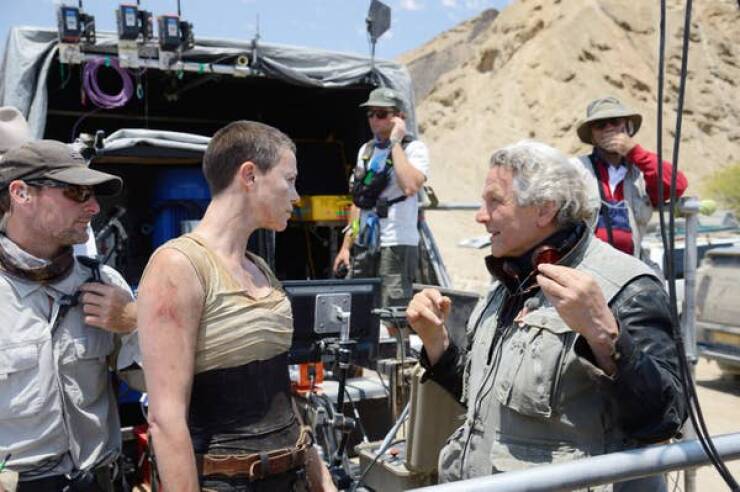 behind the scenes movies - Charlize Theron chats up director George Miller while sweatin' it out in the desert during Mad Max: Fury Road (2015).