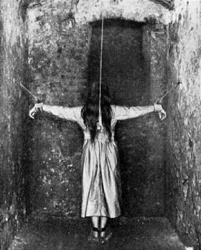 A Patient Undergoing Treatment For Mental Illness, Germany 1890. This photo depicts a woman forced into a crucifixion pose and facing a wall. The woman is a patient at a mental institution, undergoing treatment. Believe it or not, forced standing was considered a legitimate part of treatment for mental illness in 19th century Germany.