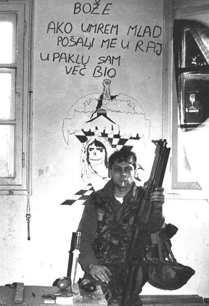 Croatian Soldier In Front Of A Wall That Says "God If I Die Young Send Me To Heaven In Hell I Have Already Been"