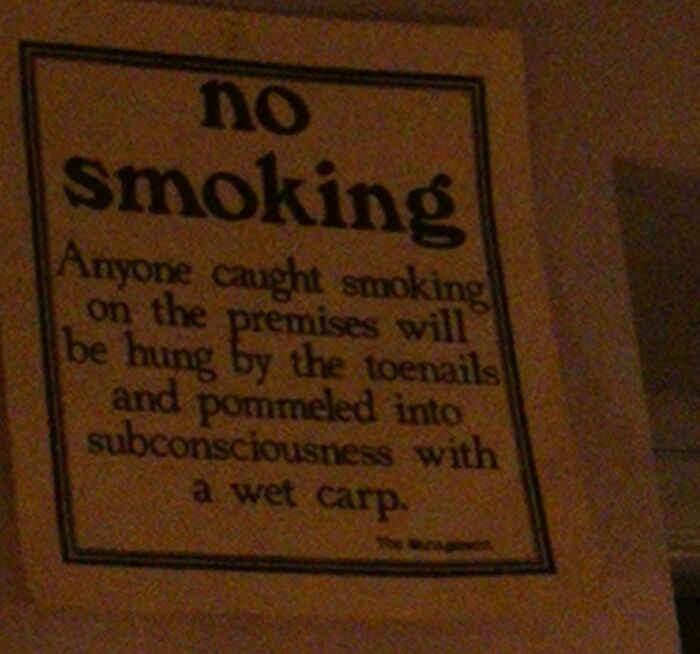 Strange threats - sign - no smoking Anyone caught smoking on the premises will be hung by the toenails and pommeled into subconsciousness with a wet carp.
