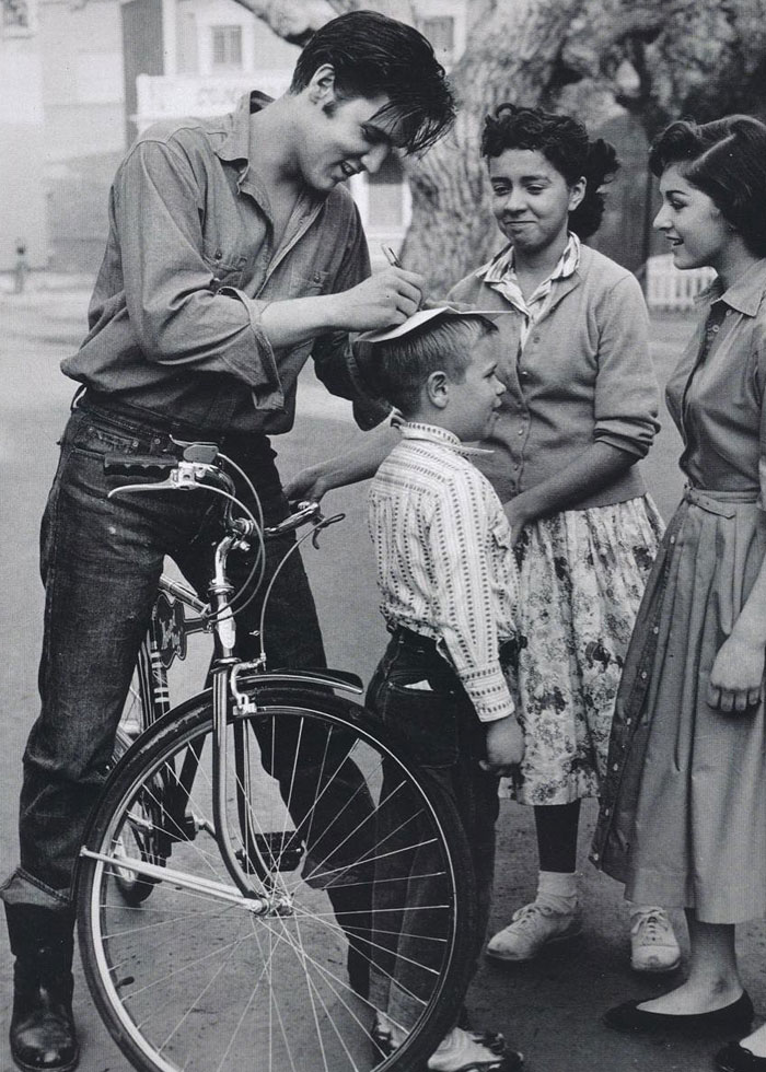 rare and fascinating celeb pics - elvis signing autograph on kids head -