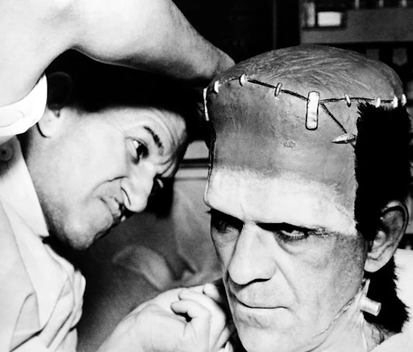 Boris Karloff gets a touchup from makeup artist Jack Pierce between scenes while filming Son of Frankenstein (1939):