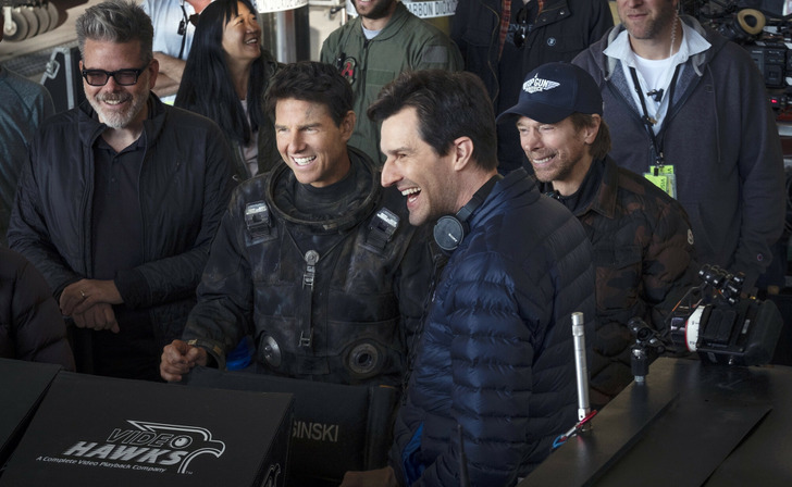 Tom Cruise laughing with the producers and director of the movie Top Gun: Maverick (2022).