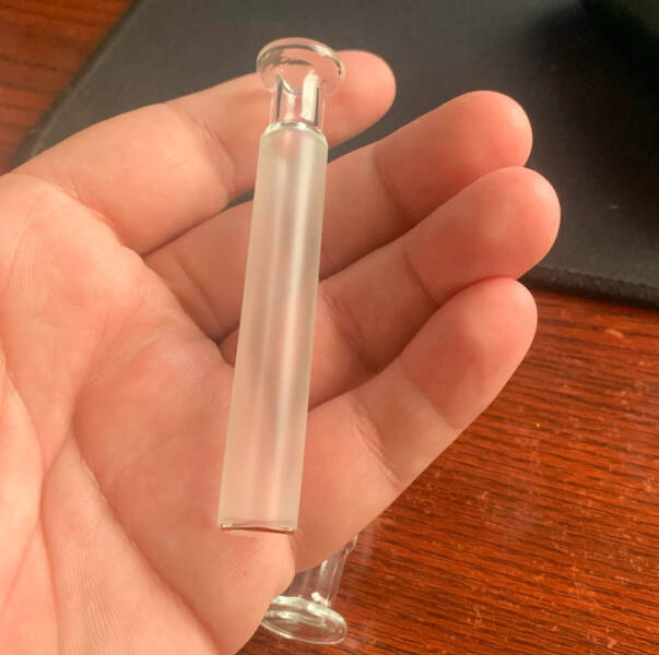 “Found this at work today, left by the overnight employee. It’s solid all around. No openings at all. Hollow glass, gold trim on one end.”

Answer: “Glass syringe plunger. We have them at work.”