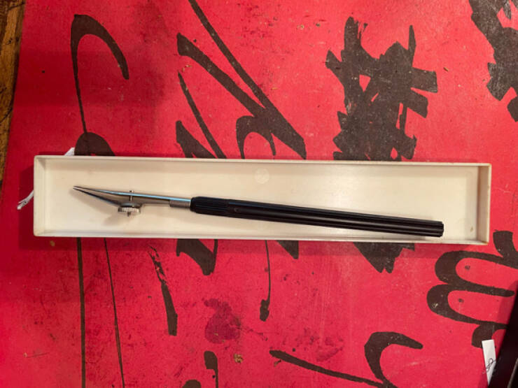 “It’s a long tool with a metal dial on the top that you can twist, possibly related to calligraphy or a type setting.”

Answer: "It’s a drafting pen."