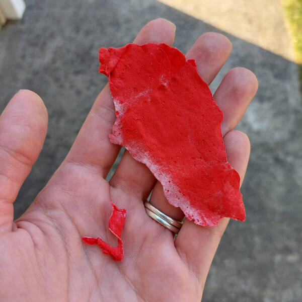 “These 2 things floated to the ground just after a large plane passed low over my house. They’re gritty and rubbery, almost like dried paint.”

Answer: "Reminds me of the flame retardant powder they have big planes fly over fires and drop, maybe a congealed chunk of it."