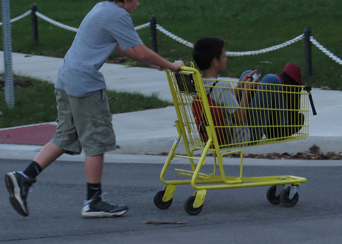 Kids sitting on steps who bolt inside when a cop car rolls by.