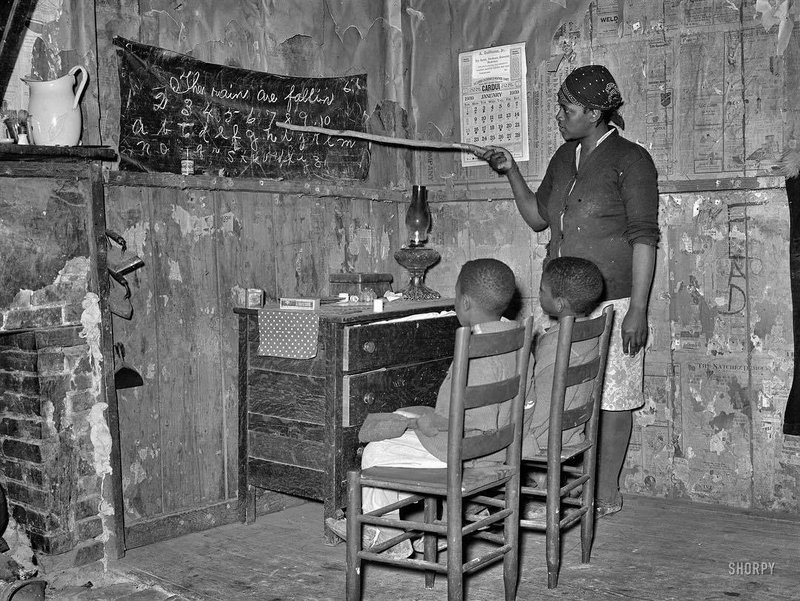 Sharecropper & mother teaching her children numbers and alphabet at home in Louisiana, 1939.