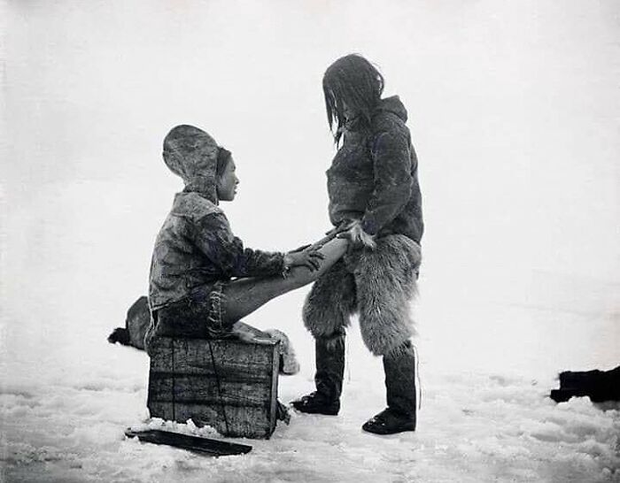 important historical pictures - inuit man warms wife's feet
