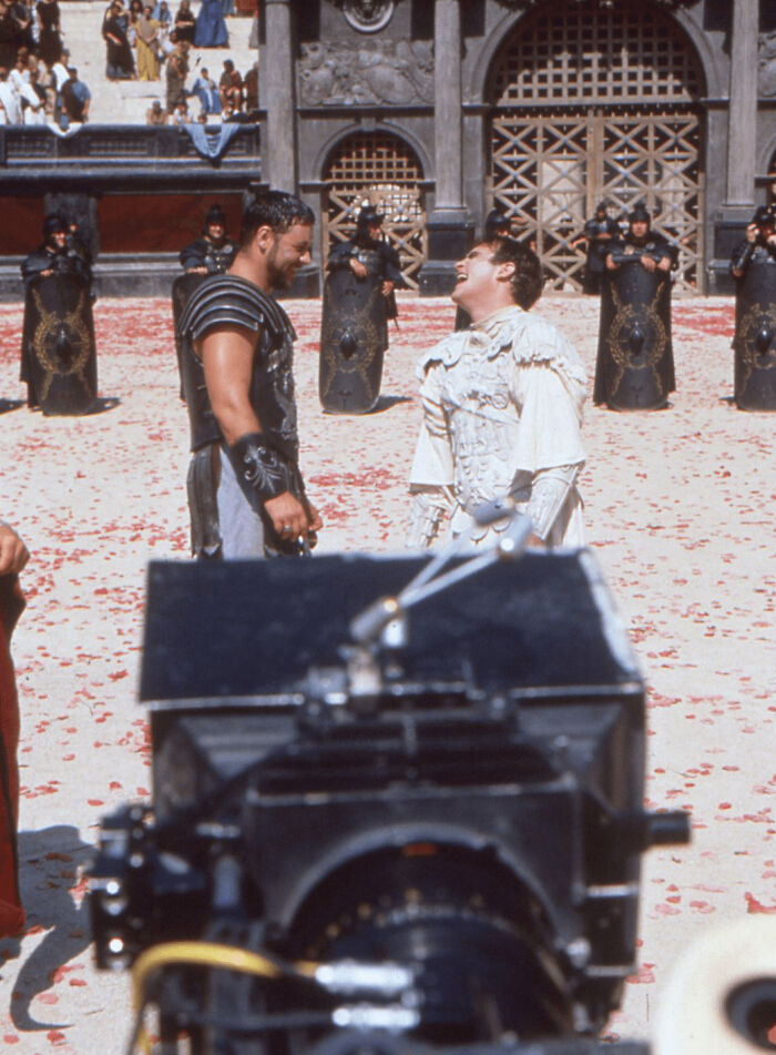 Russell Crowe, Cigarette In Hand, And Joaquin Phoenix Share A Joke While Filming Their Final Duel For 'Gladiator' (1999).