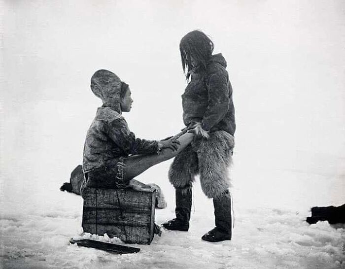 historical photographs - inuit man warms wife's feet - C