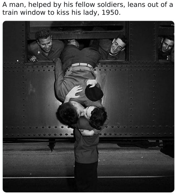 Historical pictures - goodbye kiss - A man, helped by his fellow soldiers, leans out of a train window to kiss his lady, 1950.