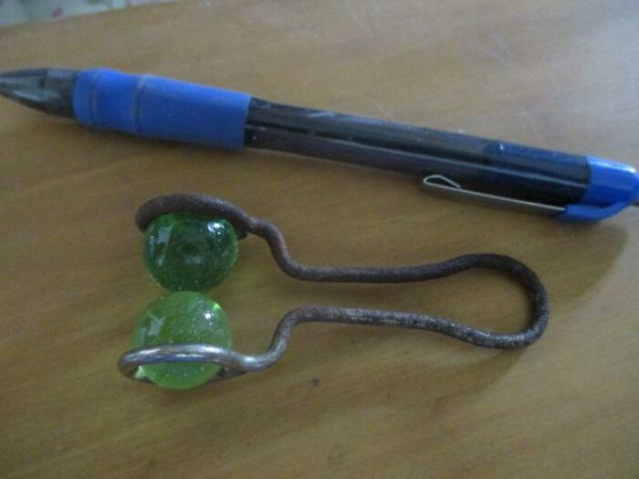 This Is A Steel Wire Frame With Two Glass Marbles. It Was Found In An Old Garage Among Various Stuff. The Marbles Can Turn Inside The Frame.
Answer: It's a razor blade sharpener.