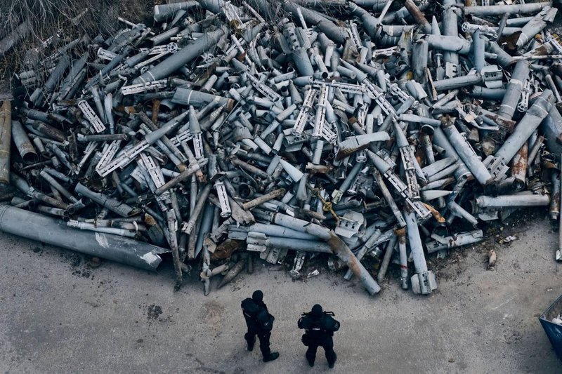 Ukrainian policemen standing next to junkyard of Russian rockets that have been falling on Kharkiv