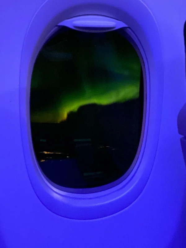 “Aurora borealis seen outside of a plane window.”