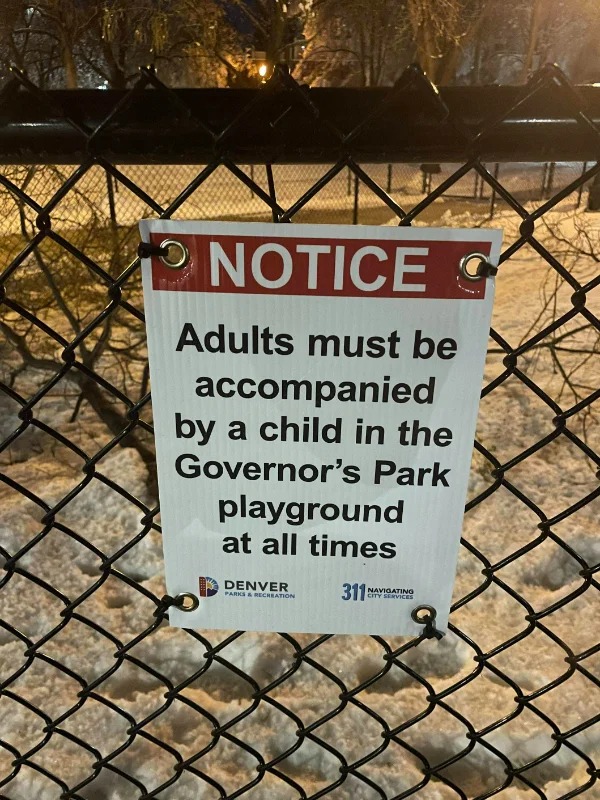 “A sign that forbids adults who are not accompanied by a child in a public park.”