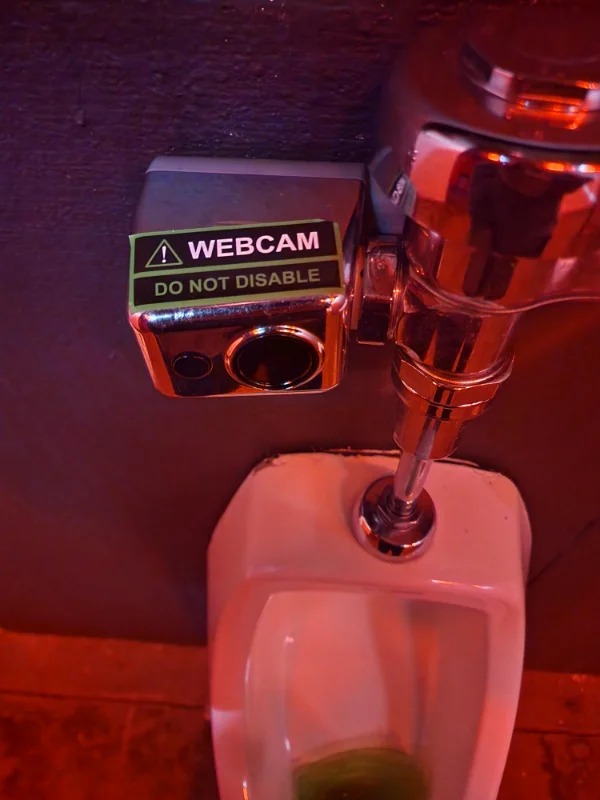 “Someone placed a Webcam sticker on this urinals flush valve at a music venues bathroom.”