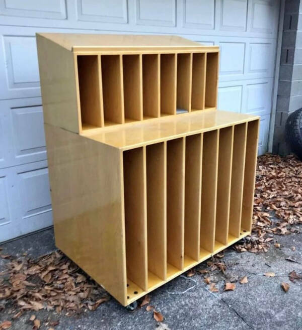 “Wooden vertical slot shelf thing. 5 ft by 4 ft. Wooden and on wheels.”

“Used for storing mat board for picture framing and art projects, whole pieces in the bottom slots and scraps, once cut, in the top. The diagonal top is used to put your artwork or print on to try different combinations.”