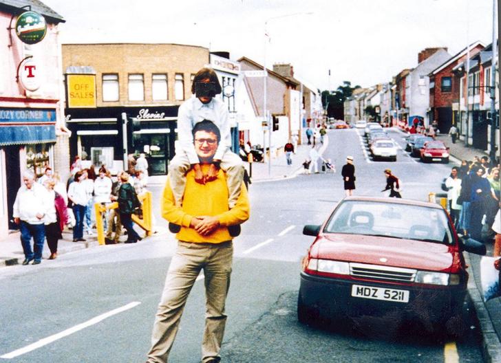 Father and son posed together for a photo in Nothern Ireland.
Almost immediately after this photo was taken, a bomb was set off in the red car beside the boy on his dad’s shoulders. The father and child survived miraculously, but the photographer and 28 others died, while around 220 were injured.