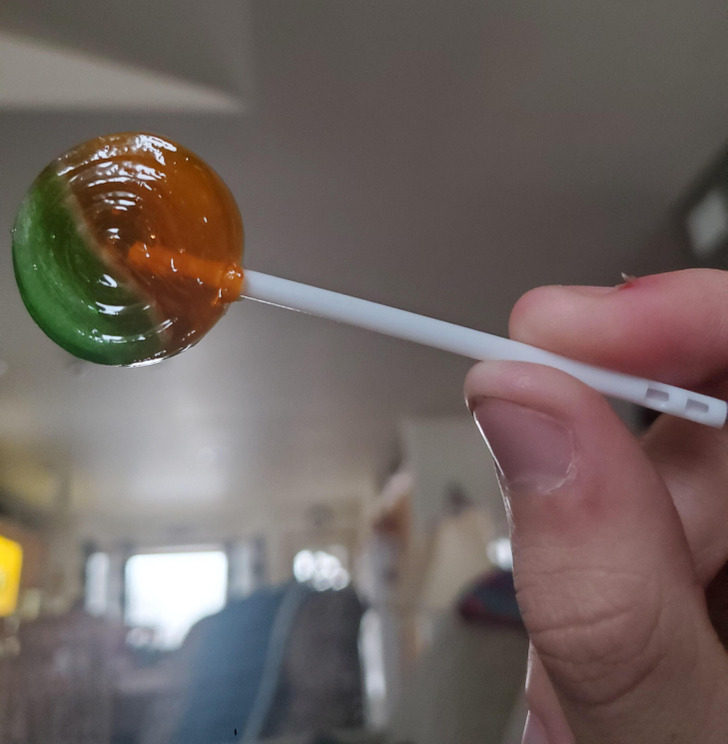 The small hole in the lollipop serves 2 important purposes. First, while it’s being made, the hot liquid is poured onto the stick and the hole helps keep the syrup in place while it’s being consumed. This prevents the candy from falling off the stick.

Second, the hole is also a safety feature, in case someone accidentally swallows the stick. The hole allows air to still enter, preventing choking.