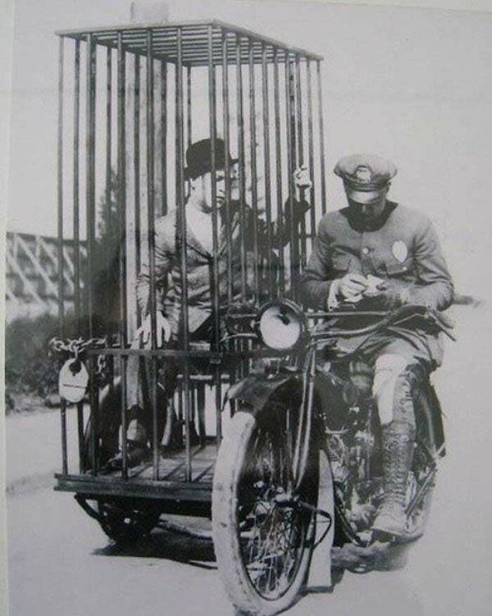 A Police Officer On A Harley-Davidson Transports A Prisoner In A Mobile Holding Cell (1921)