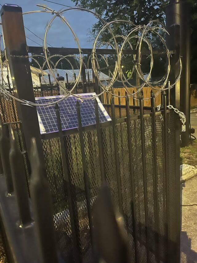 "A single solar panel guarded by a couple square feet of fencing and barbed wire"