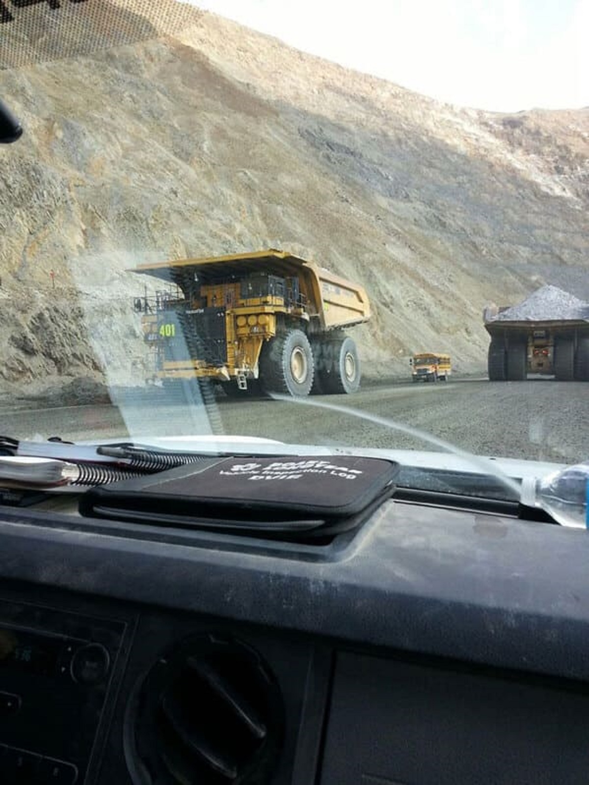 “A full-sized school bus next to haul trucks”