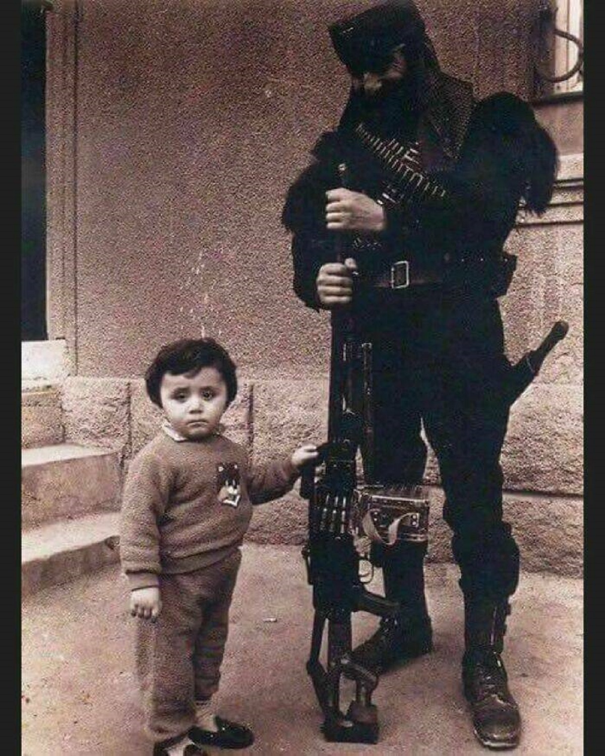 "Pavlik Manukyan, Armenian War Hero During The First Nagorno-Karabakh War In The Early 1990's, Seen During A Visit To His Family Away From The Frontline. He Is Posing Armed With A Pkm Machine Gun, Standing Next To His Son"