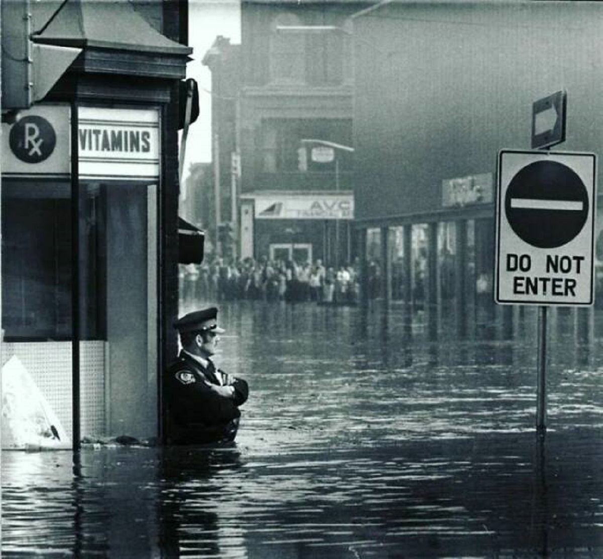 "Canadian Police Officer Guarding The Pharmacy In Waist-High Flood Waters In Galt, Ontario, 1974"