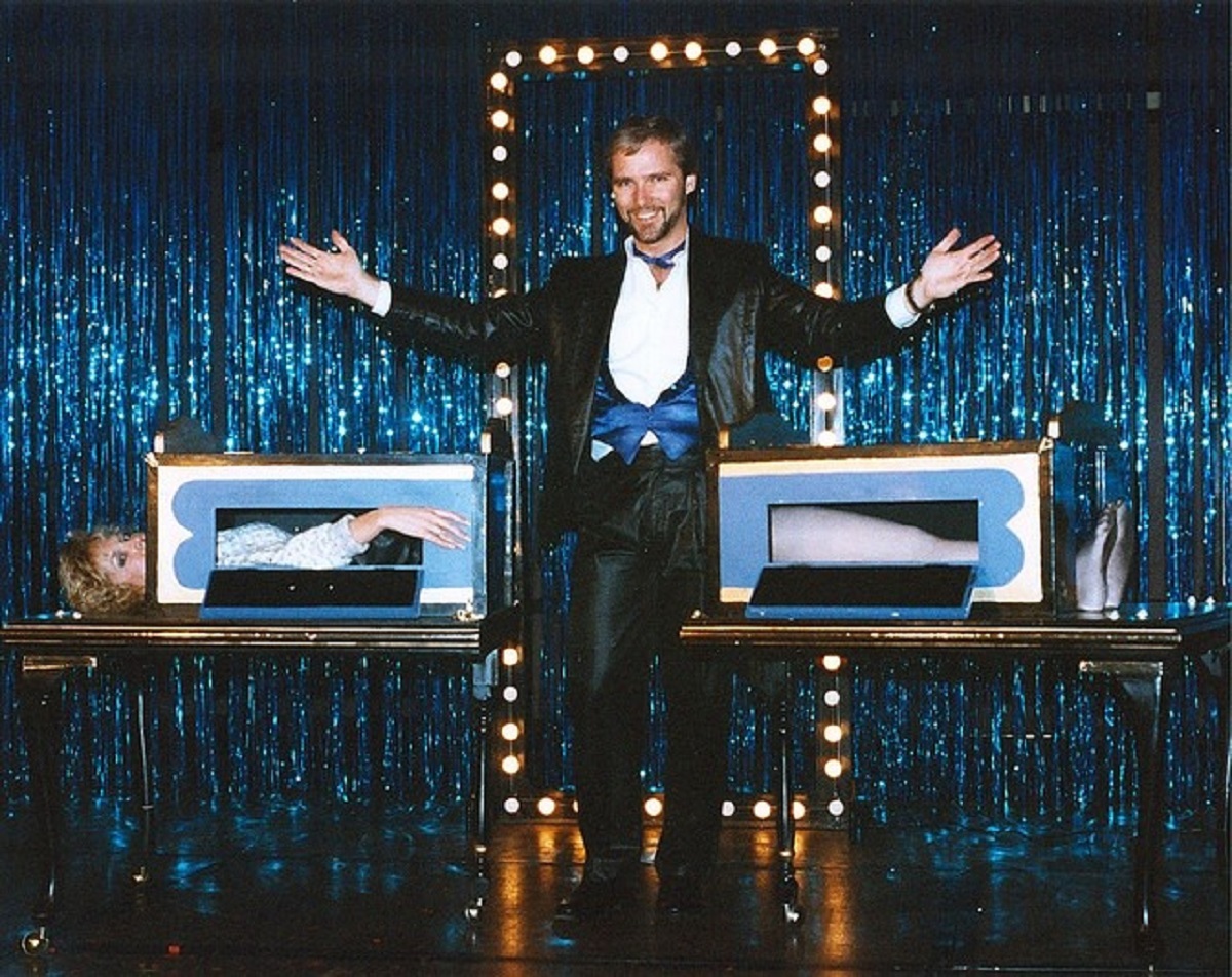 Onstage, the classic trick unfolds with the magician's assistant lying flat on a table, seemingly cut in half within a locked box. The illusion, performed before a live audience, involves the magician separating the halves. Astonishingly, the assistant appears unharmed. Behind the scenes, the trick relies on two assistants—the first in the box and the second hidden inside, extending their legs to maintain the illusion of a single unharmed assistant when the boxes are pulled apart.