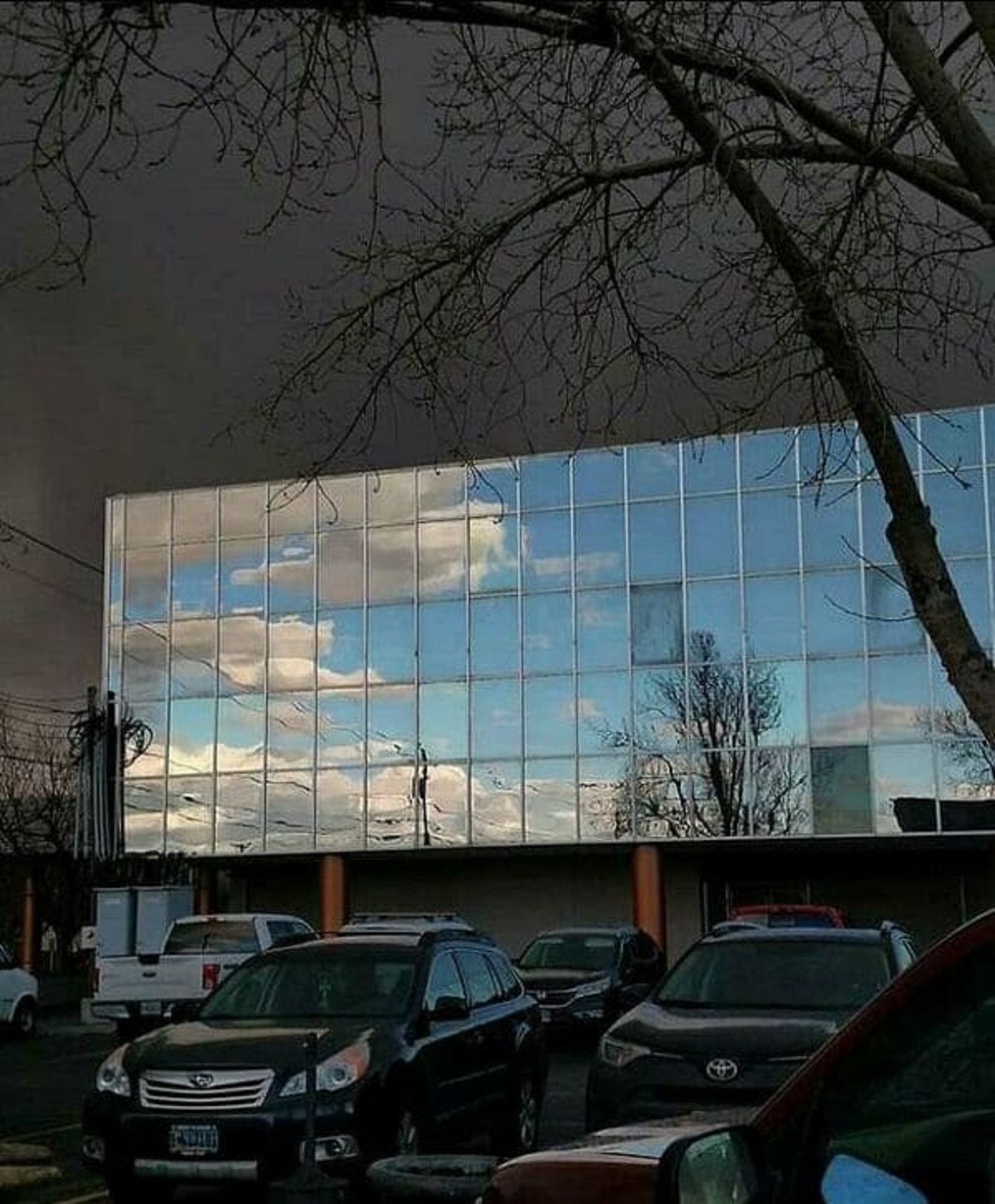 “Blue Sky Reflecting On Neighboring Building With Storm Behind It”