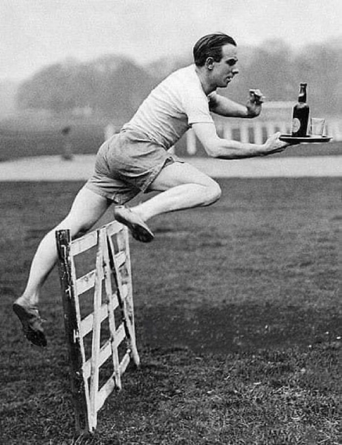 British Hurdler Percy Hodge Demonstrates The Perfect Obstacle Jump While Carrying A Bottle And A Glass On A Tray. Percy Hodge Became An Olympic Champion In The 3000m Hurdles In 1920