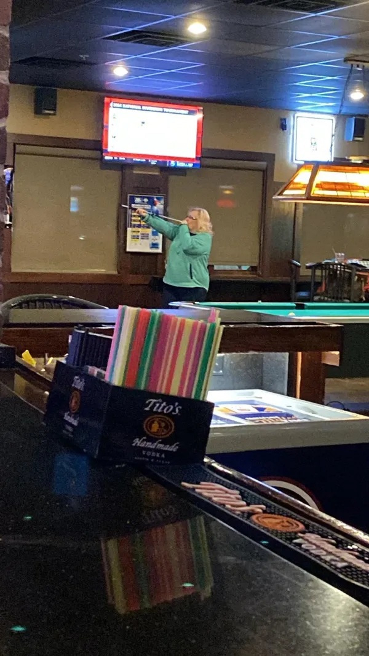 This lady at my local bar is playing darts, with a blow dart gun.