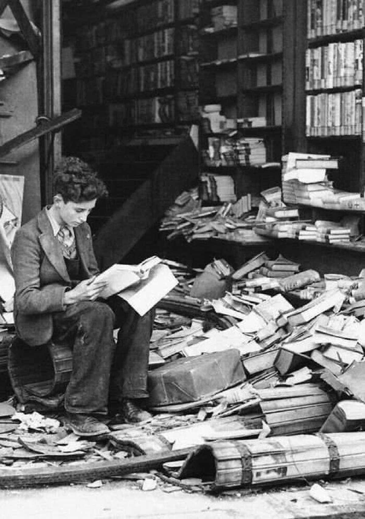 young boy sits among the rubble