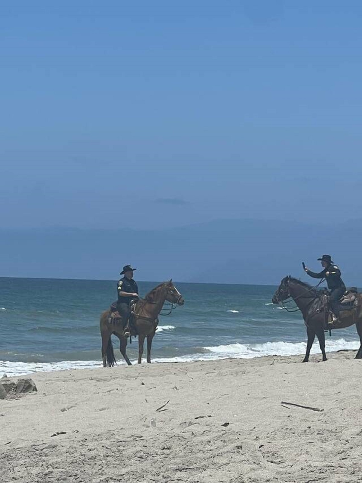 "Mounted police taking pictures at the beach."