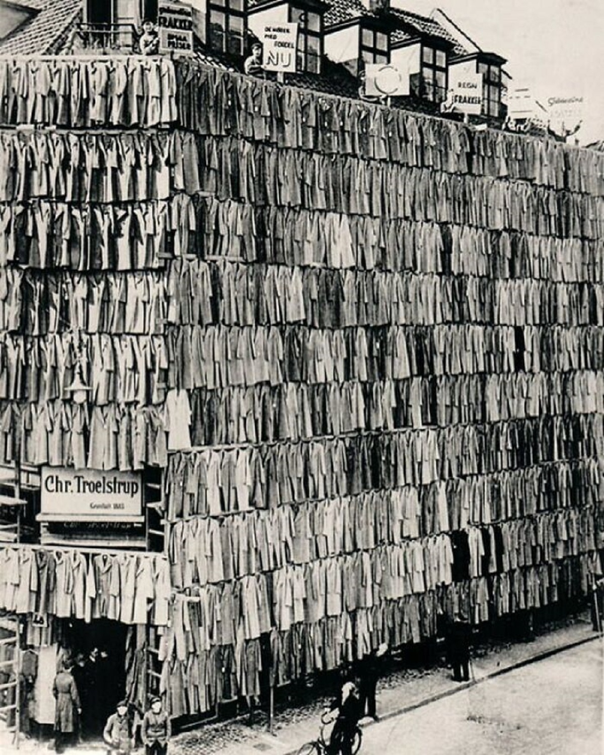 Facade of department store with five floors covered in coats. As part of a coat sale and early marketing stunt. The campaign attracted so many customers that the police had to step in. All the coats were sold. Copenhagen, Denmark. 1936.