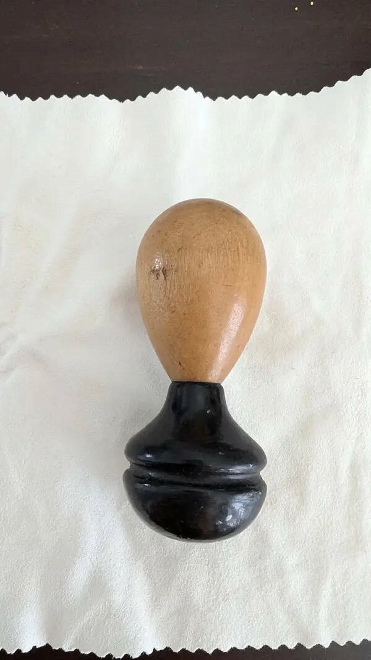 "This egg-shaped object with a black lacquered handle"

A: “That’s a darning egg. The black lacquered part is the handle, and the lighter wood is the ‘egg’ to brace clothing against when darning holes. It’s especially useful for socks!”