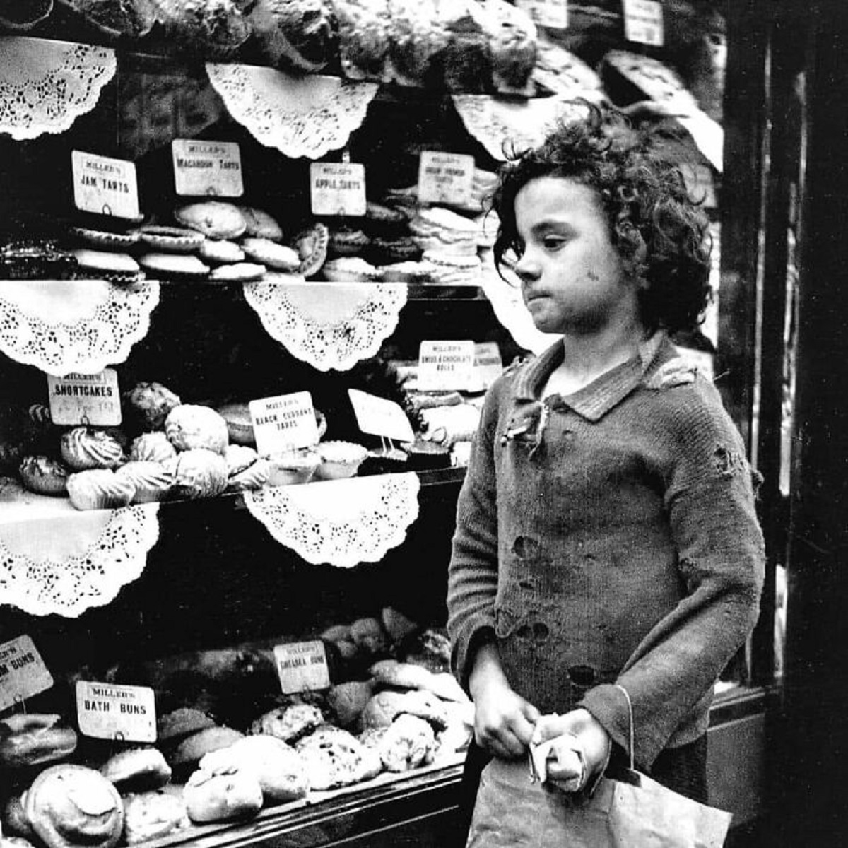 In Whitechapel, London, A Young Person's Eyes Wander Longingly Over The Freshly Baked Goods In A Bakery Window During The Financial Hardships Of The 1930s