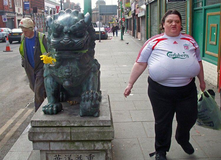 Old man in florescent green safety vest - Lion statue with yellow daffodil in his mouth - and last, but not least - Carlsberg beer advertisement on lady.