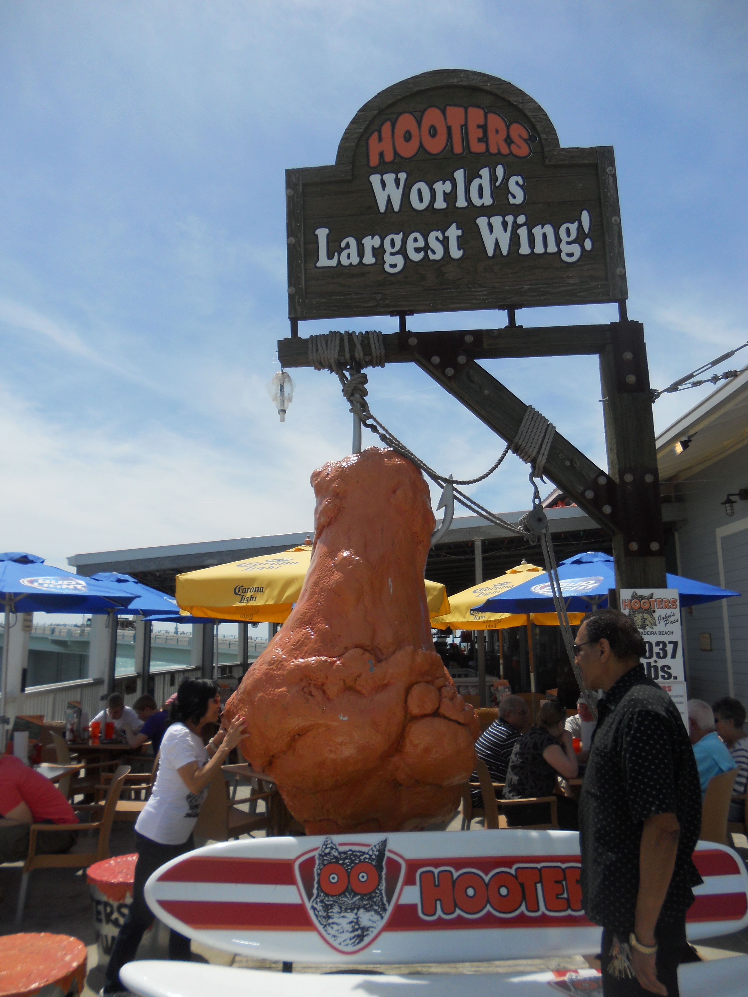 Come on novelty sign maker, you had only one job.    Girl posing with giant leg under sign that says "world's largest wing".