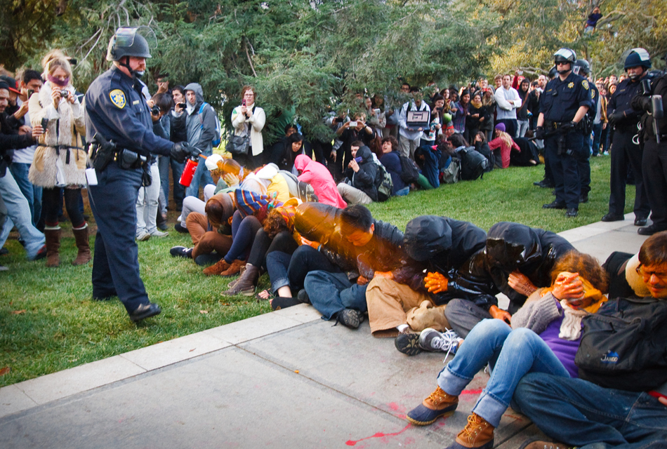 A University of California Davis police officer pepper-sprays students during their sit-in at an "Occupy UCD" demonstration in Davis, California