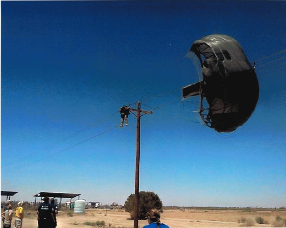 soldier hanging from parachute attached to a power pole.